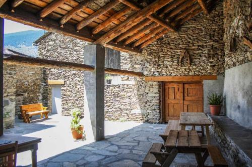 eine Außenterrasse mit Holztischen und ein Steingebäude in der Unterkunft Casa Xaupi 1 in Roní