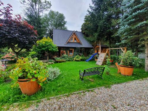 a house with a yard with plants and a playground at Domek Góralski Chatka Puchatka in Poronin