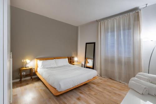 a white bedroom with a bed and a window at Pao Apartment - Navigatori in Verona