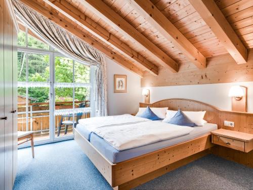 a bedroom with a bed and a large window at Waldchalets & Ferienwohnungen Allgäu in Burgberg