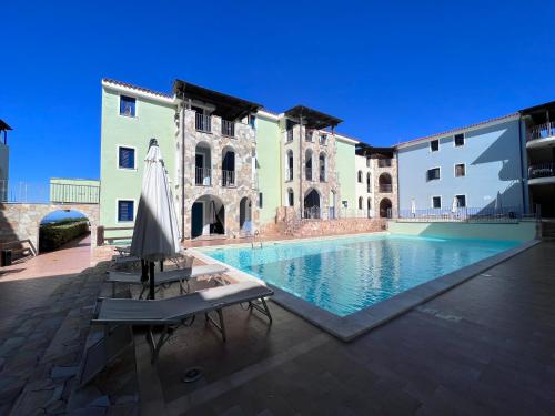 a pool in a courtyard with a umbrella and a building at Valledoria 2 int.9 in Valledoria