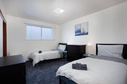 a white room with two beds and a window at Convenient 2BR Walk To Bart 10 Min To Berkeley in Richmond