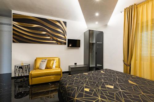 a bedroom with a bed and a yellow chair at Prezioso suites & rooms in Lecce