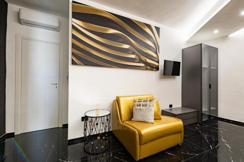 a yellow chair in a room with a painting on the wall at Prezioso suites & rooms in Lecce
