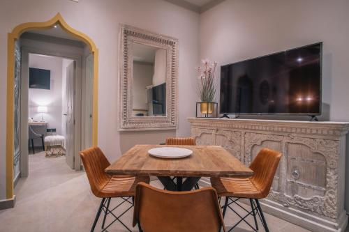 a dining room with a table and chairs and a tv at Apartamentos Turísticos La Baílla in Rota