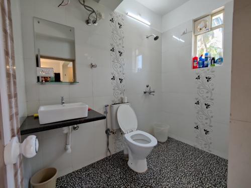 a bathroom with a white toilet and a sink at Rosean Homestay Self Service Apartments in Candolim