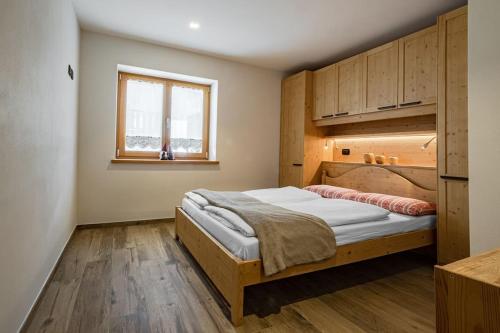 1 dormitorio con 1 cama en una habitación con ventana en Appartamento Césa Ines en Arabba