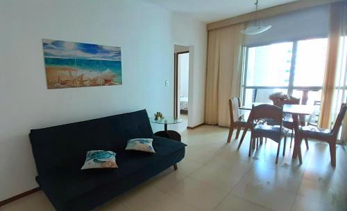 a living room with a black couch and a table at Lindo Ap Praia da Costa com Ar Condicionado in Vila Velha