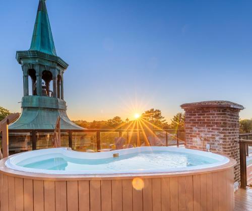 a hot tub on a deck with a clock tower at Hotel Montfort Nicolet in Nicolet