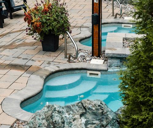 a small swimming pool with blue water in a yard at Hotel Montfort Nicolet in Nicolet
