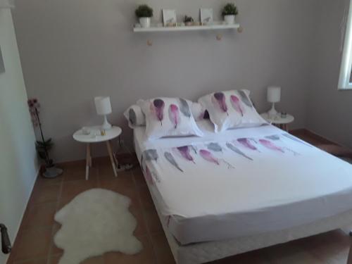 - une chambre avec un lit blanc orné de fleurs roses dans l'établissement Maison les pins, à Vedène