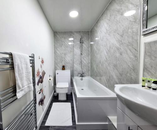 uma casa de banho com uma banheira, um lavatório e um WC. em *6B7R* Setup for your most relaxed & amazing stay + Free Parking + Free Fast WiFi* em Morley