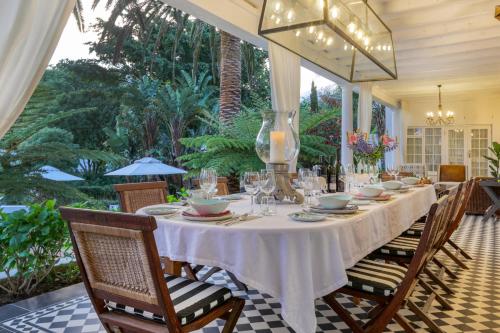 ein Esszimmer mit einem weißen Tisch und Stühlen in der Unterkunft Villa Coloniale Schumacher Luxury Retreat in Kapstadt