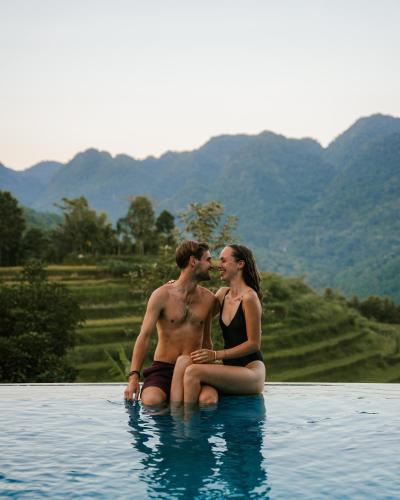 a man and a woman sitting in the water at Pù Luông Ecolodge in Pu Luong