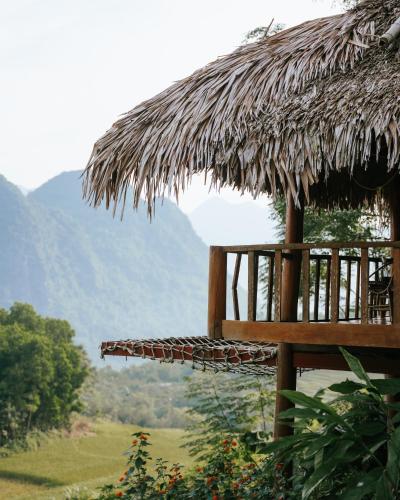 a straw hut with a view of a mountain at Pù Luông Ecolodge in Pu Luong