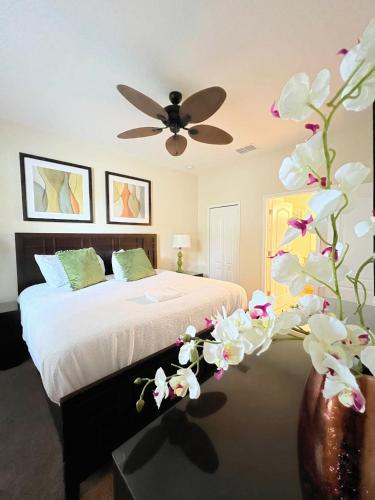 a bedroom with a bed with a ceiling fan and flowers at DWS Vacation Villas in Orlando