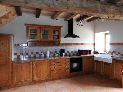 une grande cuisine avec des placards en bois et un évier dans l'établissement Maison charmante près de Nueil-les-Aubiers avec jardin, à Nueil-sous-les-Aubiers