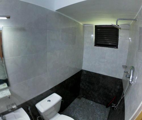 a bathroom with a white toilet and a shower at Blue Waves Madiha in Matara