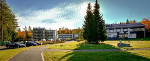 a building with a tree next to a street at Hotel Aateli Lakeside in Vuokatti