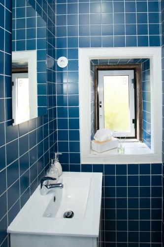 La salle de bains est pourvue de carrelage bleu, d'un lavabo et d'un miroir. dans l'établissement VisHostel, à Viseu