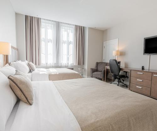 a hotel room with two beds and a television at Hotel Montfort Nicolet in Nicolet
