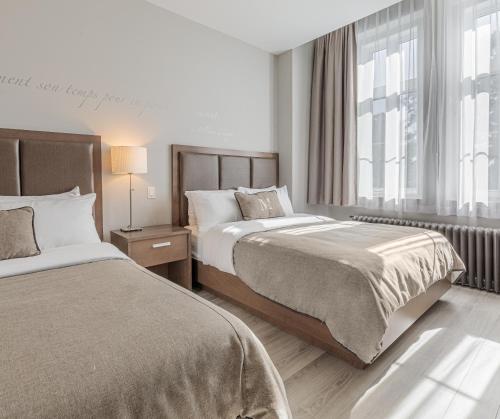 a hotel room with two beds and a window at Hotel Montfort Nicolet in Nicolet
