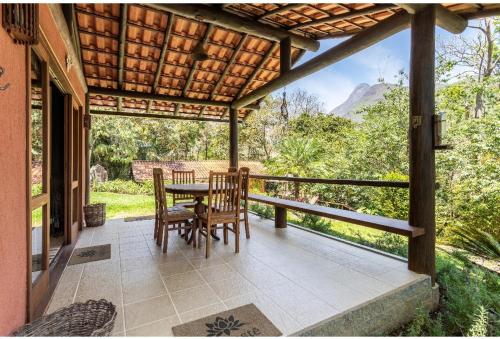 a patio with a table and chairs on a porch at Tékinfin, você chegou! Lindo sítio em Secretário! in Petrópolis