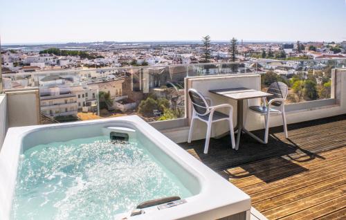 a hot tub on a balcony with a table and chairs at AP Maria Nova Lounge - Adults Friendly in Tavira