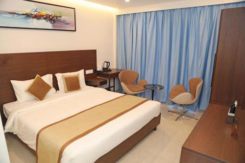 a hotel room with a bed and a table and chairs at The Zen Park Coimbatore in Coimbatore