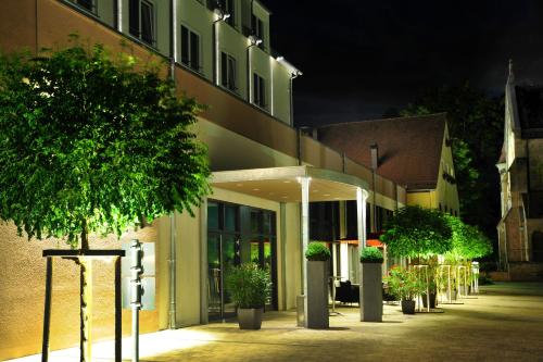 a building with a courtyard with potted trees in front of it at Landhotel Sonne in Neuendettelsau