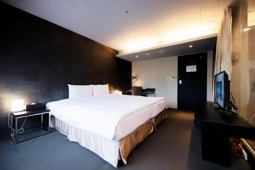 a bedroom with a large white bed and a television at 安庭台北商旅 in Taipei