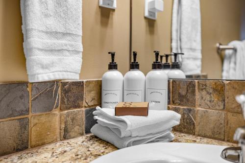 a bathroom counter with three bottles of soap and towels at Alluring Mountain View Condo -Right In The Heart Of Downtown!! Hosted by Fenwick Vacation Rentals in Canmore