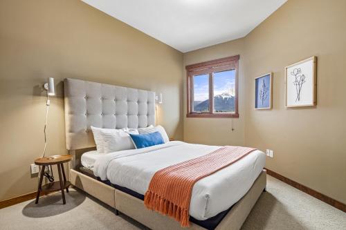 a bedroom with a large bed and a window at Alluring Mountain View Condo -Right In The Heart Of Downtown!! Hosted by Fenwick Vacation Rentals in Canmore