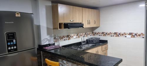 uma cozinha com um balcão preto e um frigorífico em Apartamento San Jose em Floridablanca