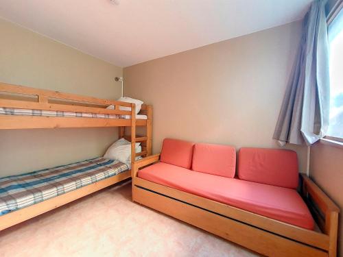 - une chambre avec 2 lits superposés et un canapé rouge dans l'établissement Duplex lumineux au pied des pistes avec balcon, parking gratuit et animaux acceptés - FR-1-344-1071, aux Menuires