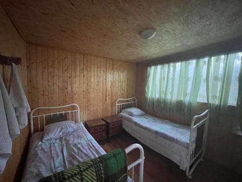 Cette petite chambre comprend 2 lits et une fenêtre. dans l'établissement Chveni Ezo, à Ambrolaouri