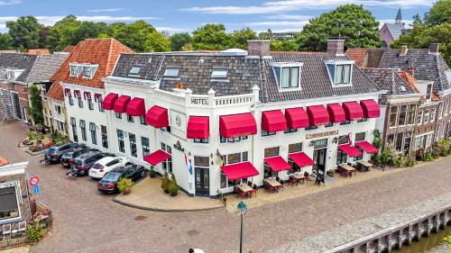 uma vista superior de um grande edifício branco com toldos vermelhos em Hotel Restaurant 't Heerenlogement em Harlingen