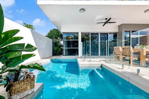 a swimming pool in a house with a dining table and chairs at Poolside Gunya Luxury Living in Fannie Bay in Darwin