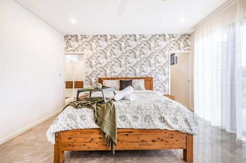 1 dormitorio con cama de madera y pared en Poolside Gunya Luxury Living in Fannie Bay en Fannie Bay
