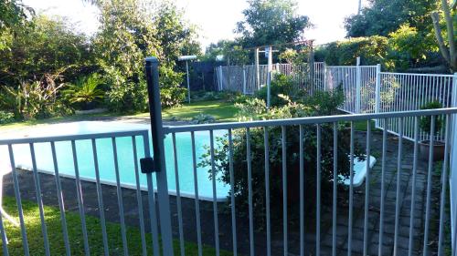 a metal fence with a pool in a yard at Ashcroft Gardens Bed & Breakfast in Napier
