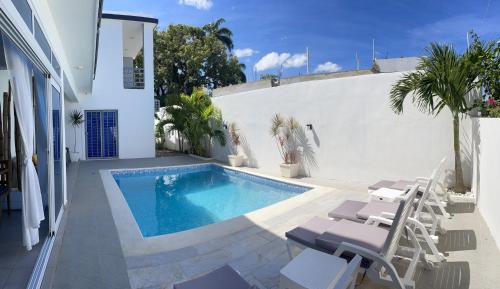 a swimming pool in a yard with chairs and a house at Gaia Residence Deluxe in San Felipe de Puerto Plata