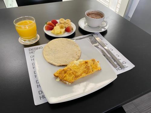 Un plato de comida con una tortilla y fruta en una mesa. en Hotel Austral Suites By GHO Hoteles, en Cali