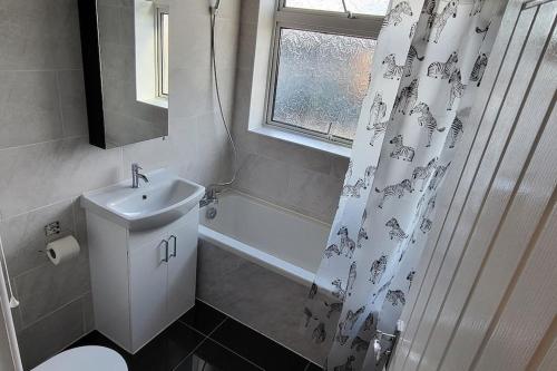 a bathroom with a sink and a shower curtain at Newly refurbished 3 bedroom flat in Bedworth