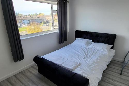 a bed in a room with a window at Newly refurbished 3 bedroom flat in Bedworth