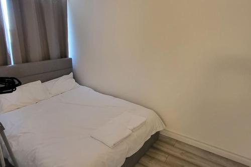 uma pequena cama com lençóis brancos e almofadas num quarto em Newly refurbished 3 bedroom flat em Bedworth