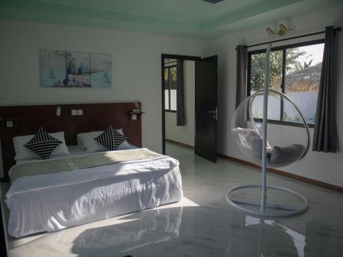 a bedroom with a bed and a chair and a mirror at Clouds Beach Retreat Laamu Gan in Gan