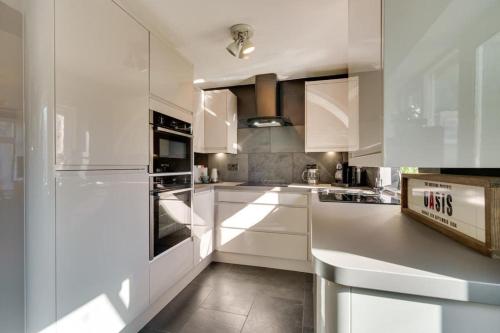 uma cozinha branca com armários e electrodomésticos brancos em Mews Cottage Arnside - 2 Bedroom Cottage em Arnside