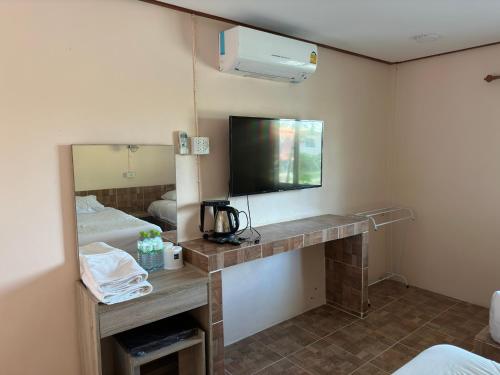um quarto de hotel com uma televisão e uma cama em สวนสบายปลายนารีสอร์ท em Ban Hin Lat