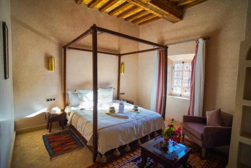a bedroom with a canopy bed and a chair at Kasbah Hnini in Igdourane