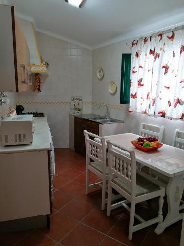 a kitchen with a white table and chairs and a sink at A Casa da Carolina in Mértola